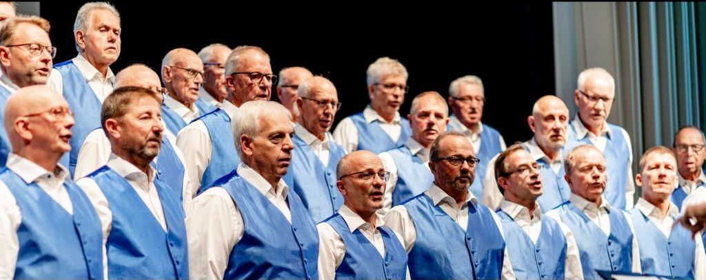 Sänger des Männerchors in blauen Westen beim Singen auf der Bühne